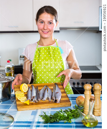 Woman putting sprats in baking 19956921
