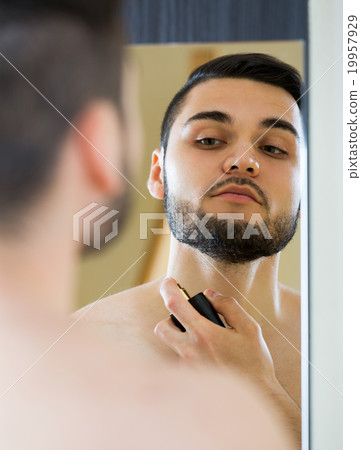 Young guy using perfume at home. 19957929