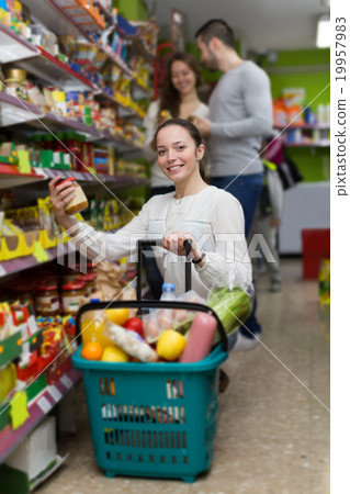 customers standing near shelves with canned goods at shop customers standing near shelves with canned goods at shop 19957983