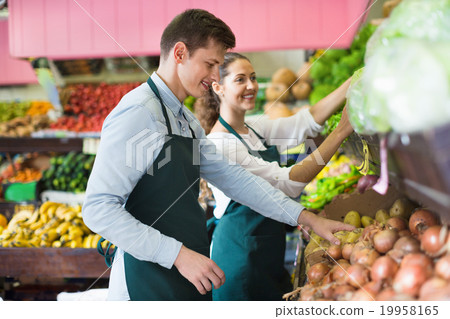 Smiling sellers having vegetables and fruits on displays 19958165