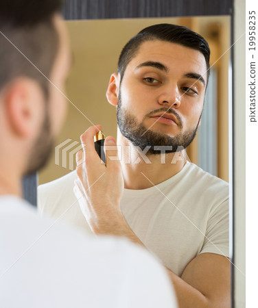 Young guy using perfume at home. Young guy using perfume at home. 19958235