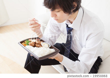 A young businessman who eats a convenience box lunch A young businessman who eats a convenience box lunch 19958868