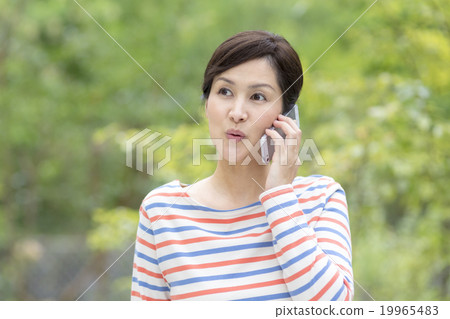 A woman in his 40's speaking on a smartphone 19965483