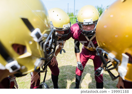 American Football players at strategy huddle 19991188