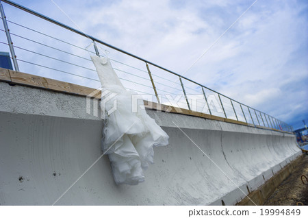 Nice bridal dress is hanging on the pier fencing. 19994849