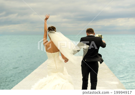 Nice newlyweds are walking on the pier. 19994917