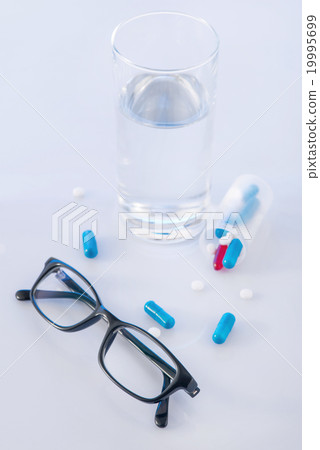 Water glass, pills and eyeglasses on the surface. Water glass, pills and eyeglasses on the surface. 19995699