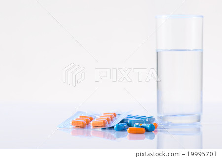 Glass of water with medicines on the surface. Glass of water with medicines on the surface. 19995701