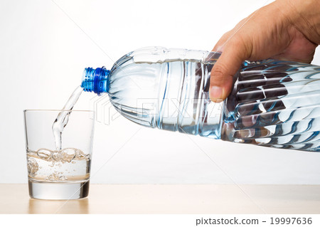 Hand pouring mineral water from bottle into glass Hand pouring mineral water from bottle into glass 19997636