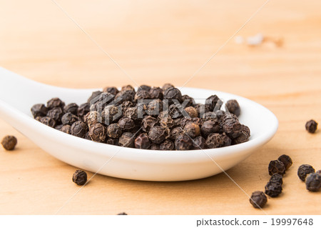 Spoonful of black pepper corns on wooden surface Spoonful of black pepper corns on wooden surface 19997648
