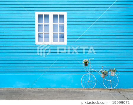 White window on blue wall with bike shaped stand. 19999071