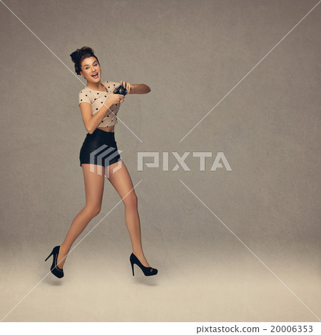 Girl jumping with retro camera 20006353