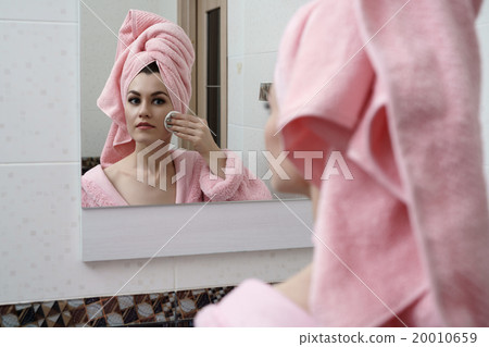 Beautiful woman cares for skin in mirror Beautiful woman cares for skin in mirror 20010659