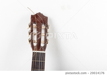 Old classical acoustic guitar on white wall background Old classical acoustic guitar on white wall background 20014176