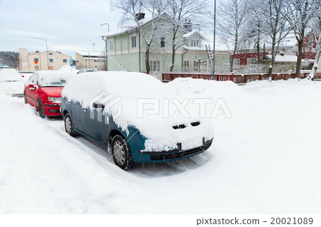 Cars covered with snow parked along winter street 20021089