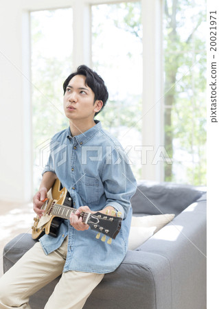 Male in her 20s playing electric guitar Male in her 20s playing electric guitar 20021971
