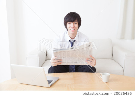 A young businessman reading a newspaper 20026486