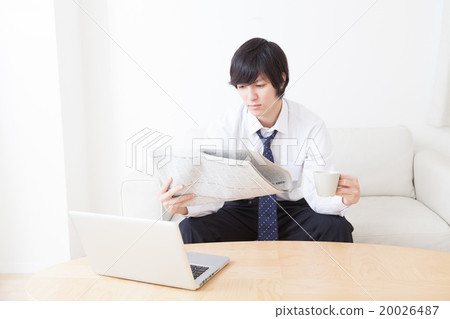 A young businessman reading a newspaper 20026487