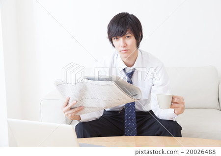 A young businessman reading a newspaper 20026488