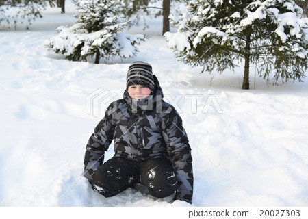 Teen boy sitting on   snow in the winter forest 20027303