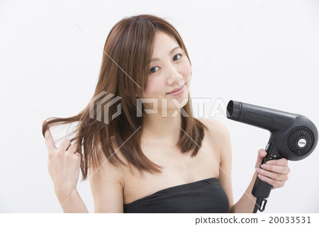 A woman using a hair dryer A woman using a hair dryer 20033531