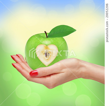 Green apple in woman hand over blurred nature Green apple in woman hand over blurred nature 20052206