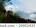 White man with hat walking at cliff above clouds 20052435