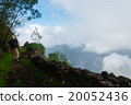 White man with hat walking at cliff above clouds 20052436