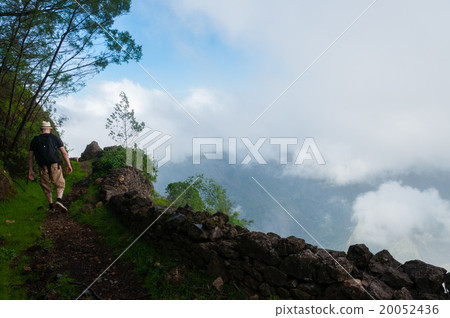 White man with hat walking at cliff above clouds White man with hat walking at cliff above clouds 20052436
