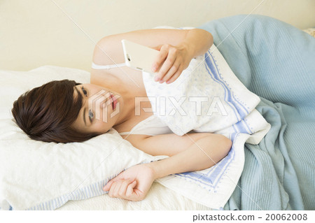 一位年輕的女士在床上睡覺時操作智能手機 20062008