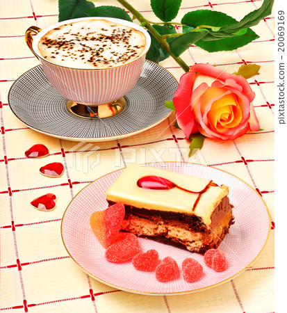 Cap of coffee, a rose and a cake on the tablecloth 20069169