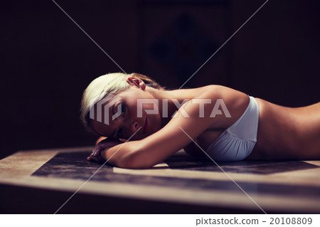 young woman lying on hammam table in turkish bath 20108809