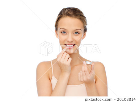 smiling young woman applying lip balm to her lips 20108814