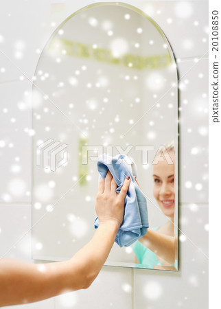 close up of happy woman cleaning mirror with rag 20108850