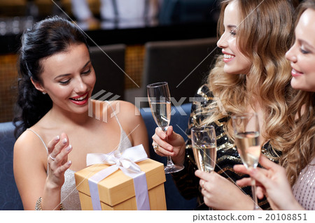 happy women with champagne and gift at night club 20108851