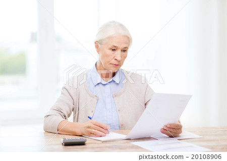 senior woman with papers and calculator at home 20108906