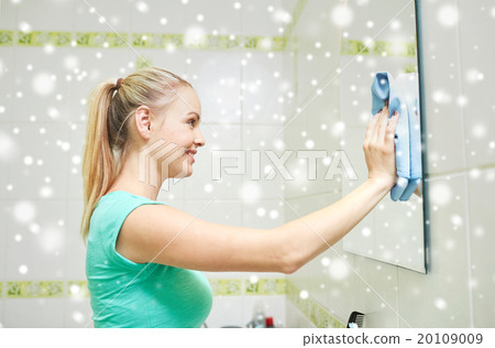 happy woman cleaning mirror with rag 20109009