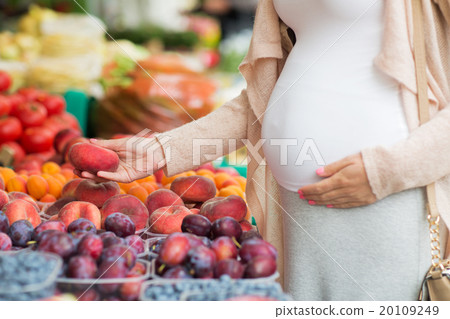 pregnant woman choosing fruits at street market pregnant woman choosing fruits at street market 20109249