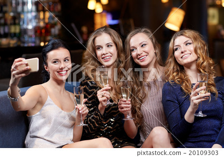 women with champagne taking selfie at night club 20109303