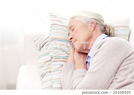 happy senior woman sleeping on pillow at home 20109305