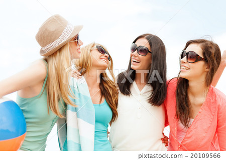 smiling girls with ball and towel on the beach 20109566