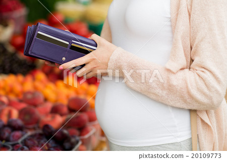 pregnant woman with wallet buying food at market 20109773