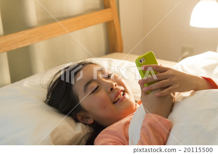 A girl watching a smartphone in bed 20115500