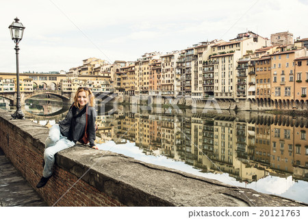 Young tourist woman is sitting on the wall in front of the Ponte Young tourist woman is sitting on the wall in front of the Ponte 20121763