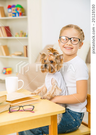 Little girl with her dog at the desk. 20128580