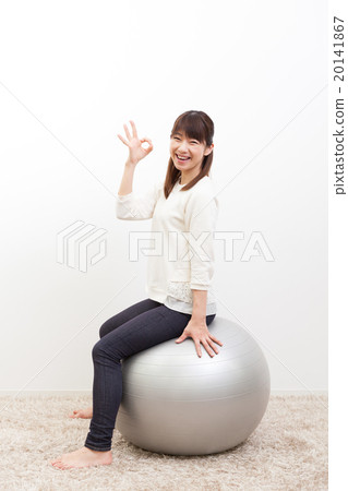 A young woman riding a balance ball 20141867
