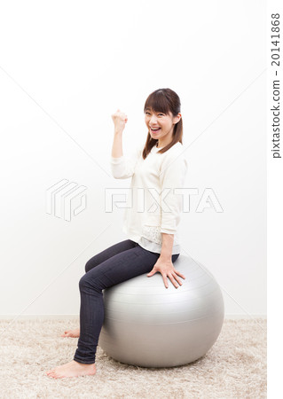 A young woman riding a balance ball 20141868