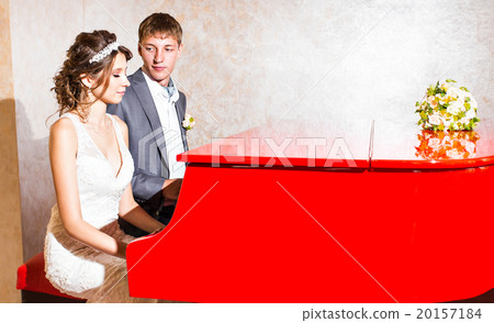 charming wedding couple playing on a red piano in charming wedding couple playing on a red piano in 20157184