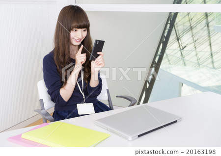 A woman watching a smartphone (office image) 20163198