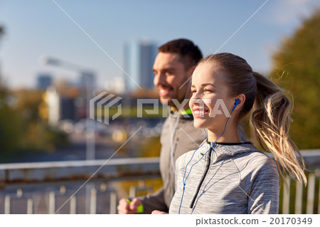 happy couple with earphones running in city 20170349